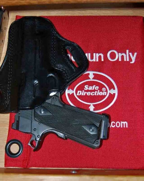 A gun is laying on the ground next to a holster.