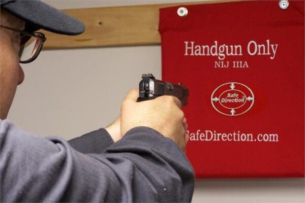 A person holding a gun in front of a red sign.